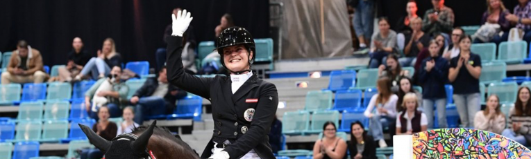 Dressurreiterin winkt mit der Hand, Publikum in der Arena in Wien